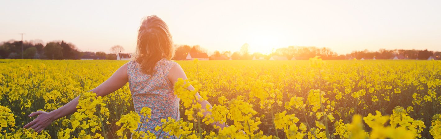 A woman standing in a field of yellow flowers.