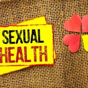A yellow sign that says sexual health next to paper hearts.