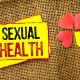 A yellow sign that says sexual health next to paper hearts.