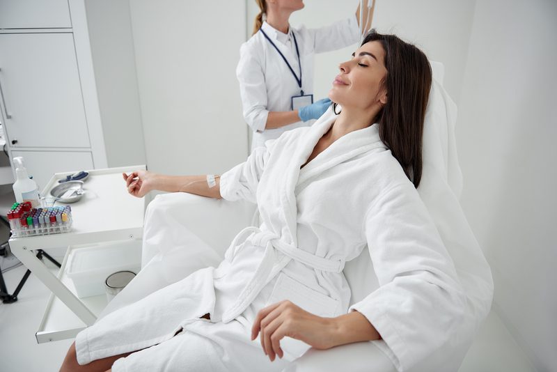 A woman in white robe sitting on top of a chair.