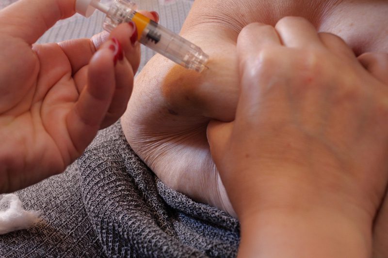 A person is getting an injection in their hand.