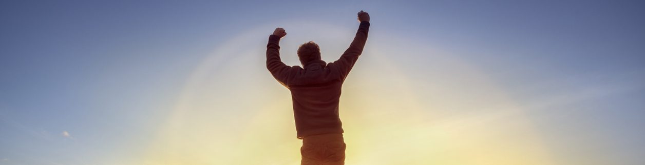 A man standing in the sun with his arms raised. A man standing in the sun with his arms raised.